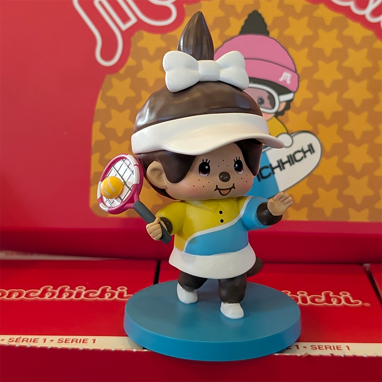 Sekiguchi Monchhichi Tennis Player vinyl figure in yellow and blue outfit with racket on blue display stand.