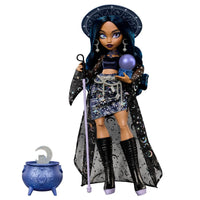 Doll dressed as a sorceress with star and moon patterns, holding a staff and crystal ball next to a cauldron prop.