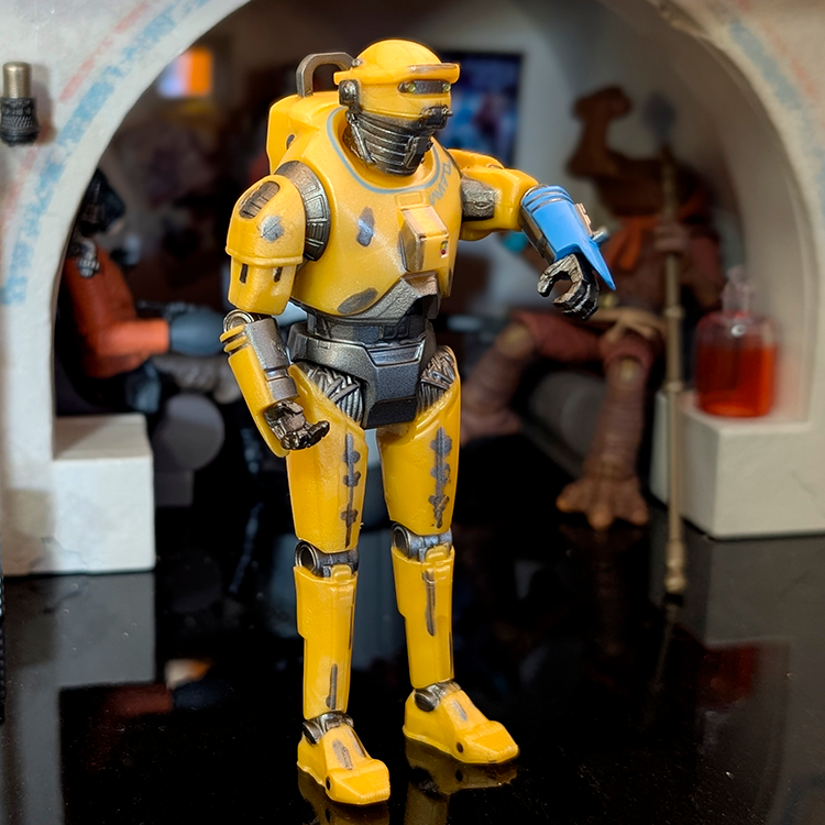 Hasbro Star Wars NED-B 3.75 inch Droid Factory action figure detailed in yellow with blue arm piece on display