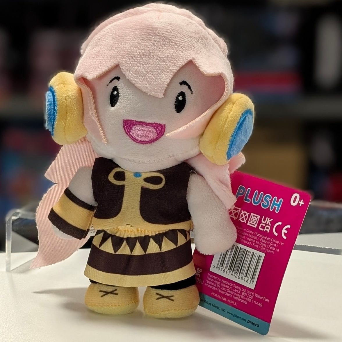 UCC 6-inch Megurine Luka plush with pink hair, yellow and blue headphones, smiling with brown and beige outfit