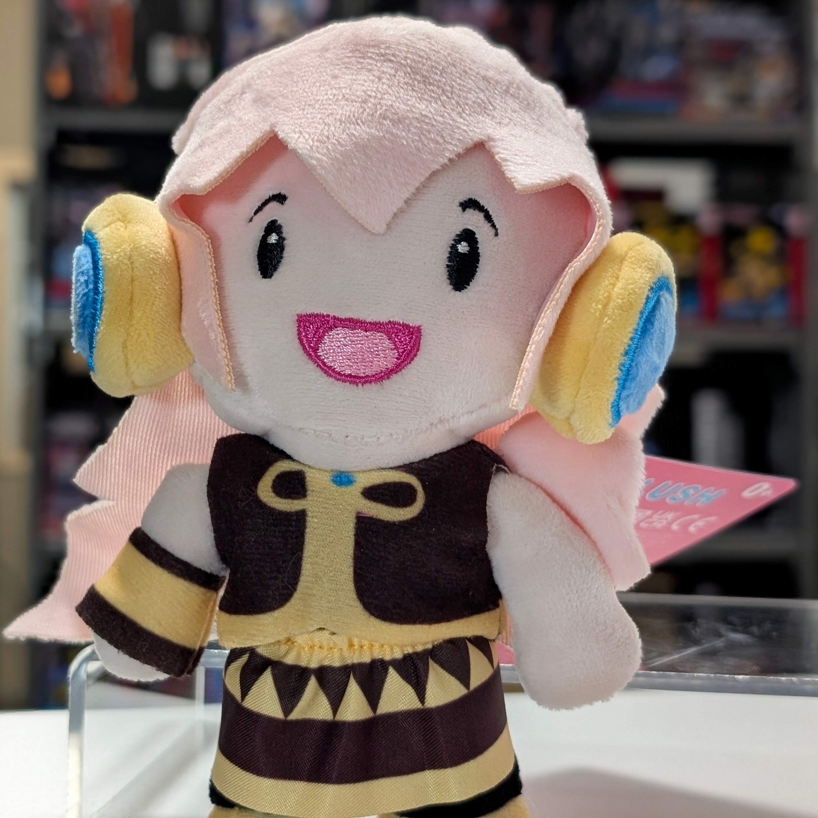 UCC 6-inch Megurine Luka plush with pink hair, yellow and blue headphones smiling with detailed outfit and tag visible