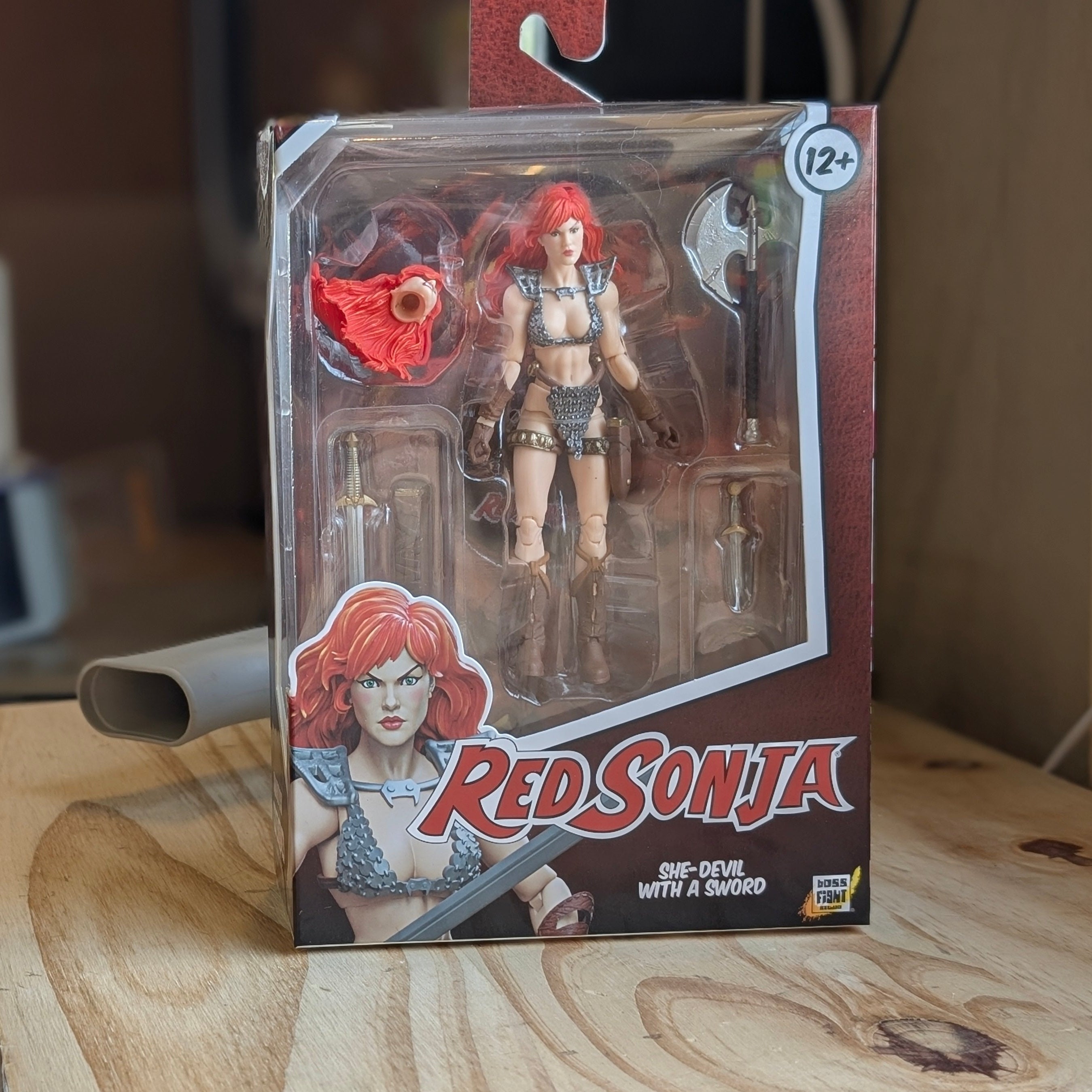 Red Sonja action figure in packaging on a wooden surface