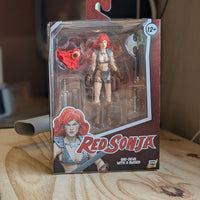 Red Sonja action figure in packaging on a wooden surface