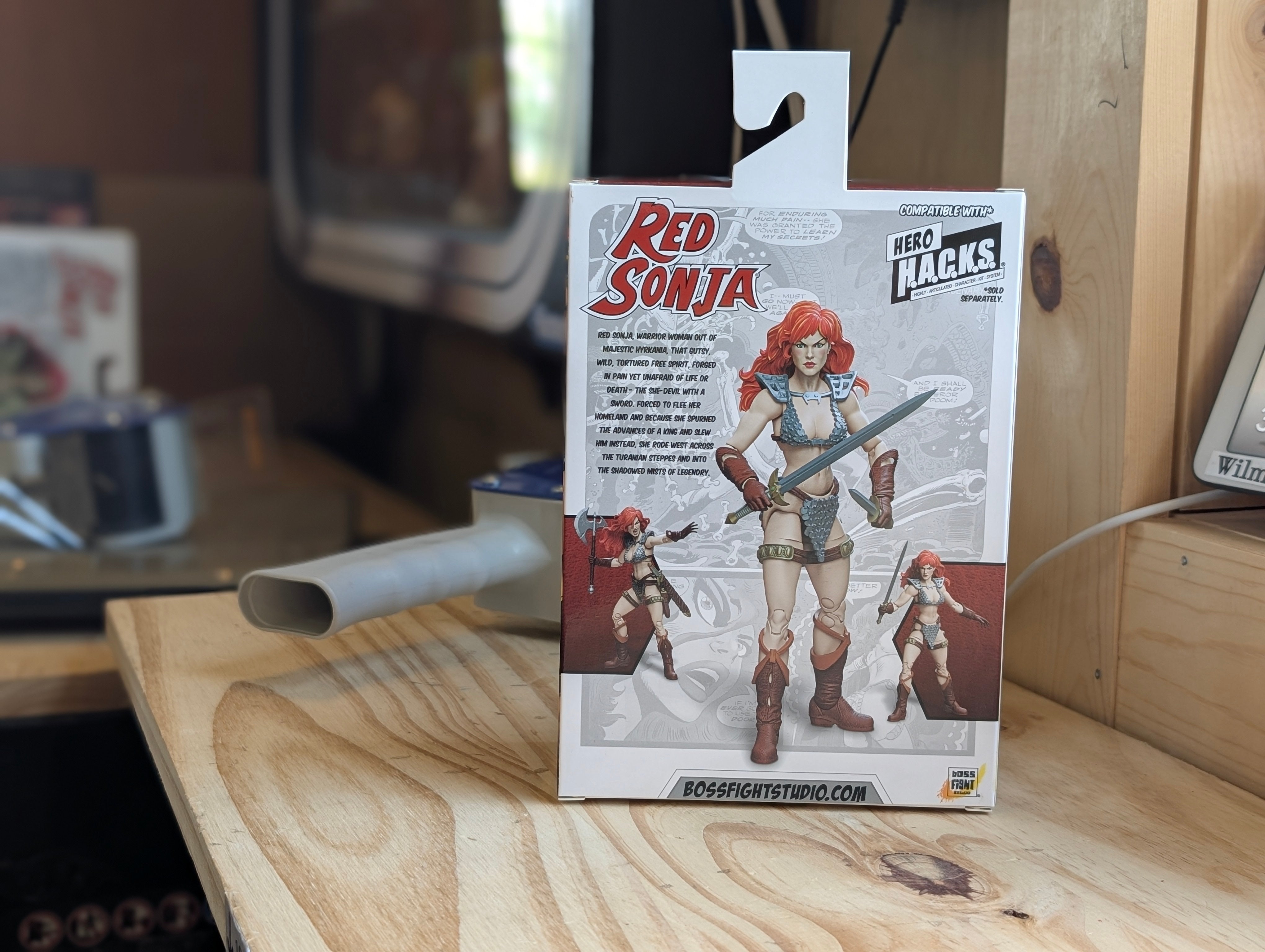 Action figure packaging with 'Red Sonja' on a wooden surface