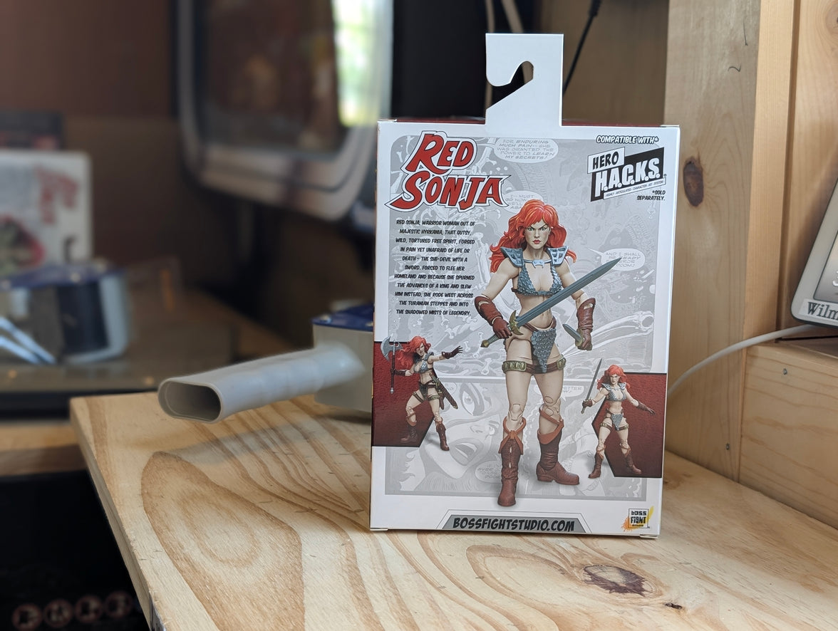 Action figure packaging with 'Red Sonja' on a wooden surface