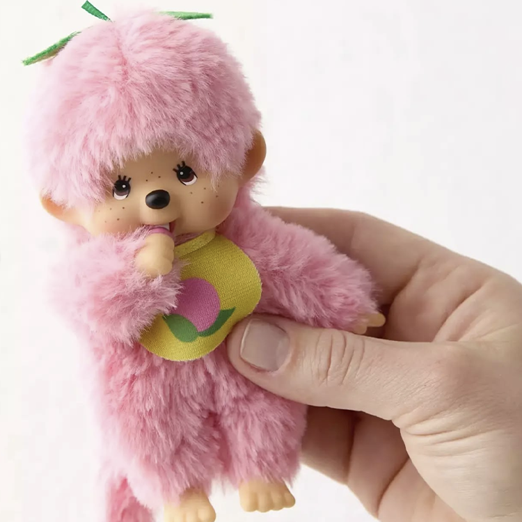 Sekiguchi Monchhichi 5-inch peach pink plush with soft fur, plastic face, hands, feet, and fruit bib held in hand.