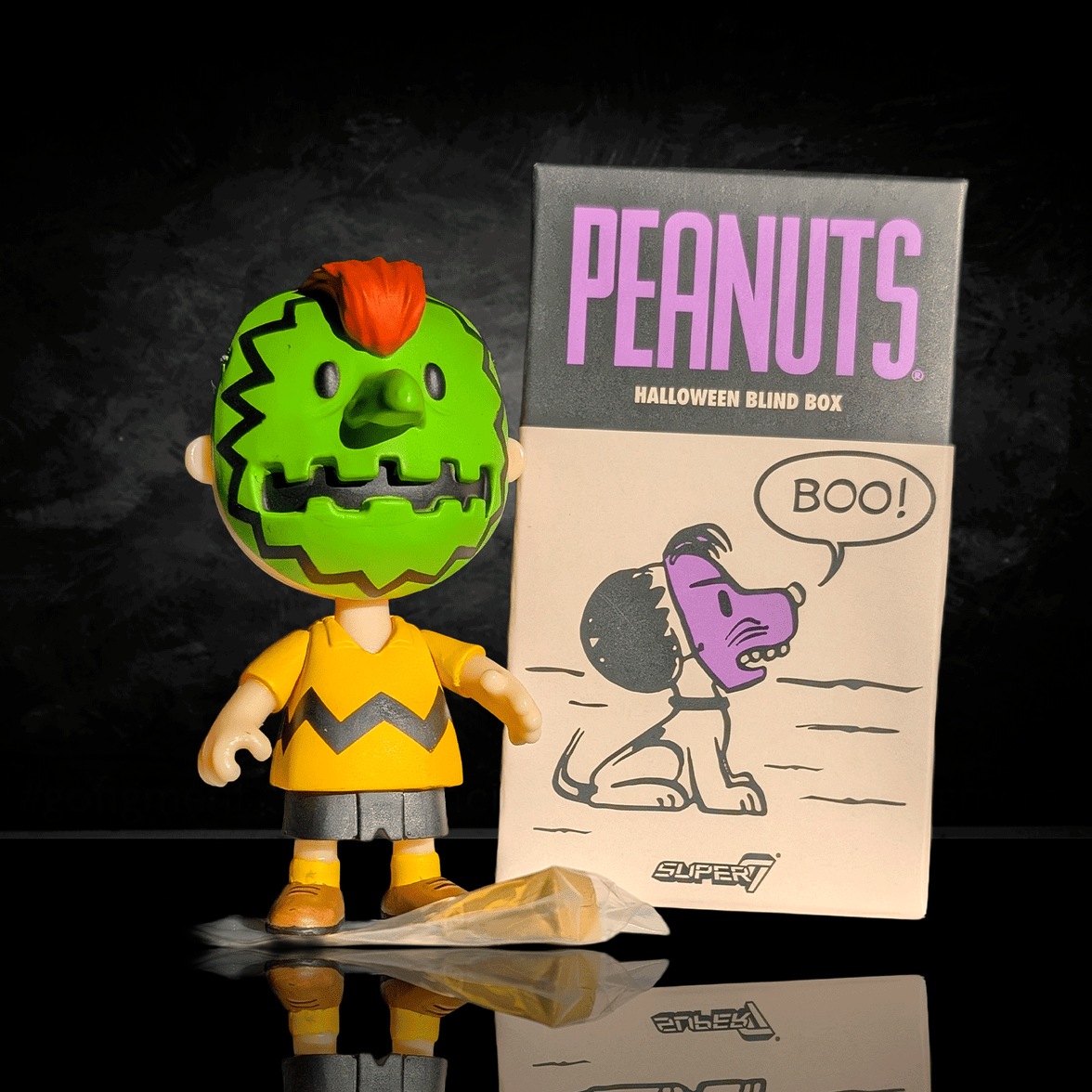 Go Figment Peanuts Halloween ReAction figure with green mask and orange hair standing beside themed blind box packaging.