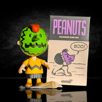 Go Figment Peanuts Halloween ReAction figure with green mask and orange hair standing beside themed blind box packaging.