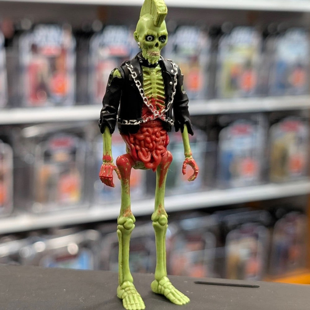 Super7 neon green male zombie figure with exposed intestines wearing black jacket with chains standing on display