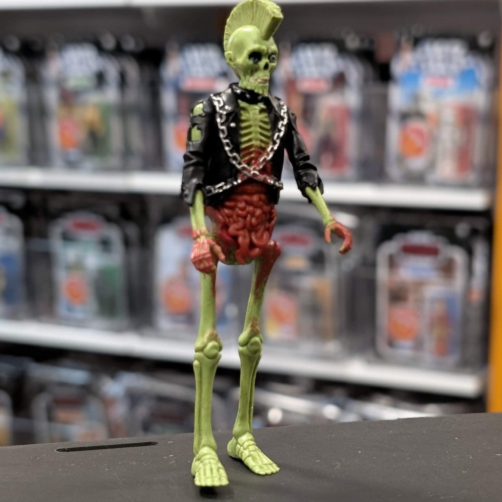 Super7 neon green male zombie figure with exposed ribs, intestines, mohawk, and black jacket with chains on display