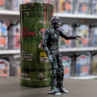 Super7 metallic blue tar-covered Tarman zombie figure with skeletal details posed in front of green collectible tube