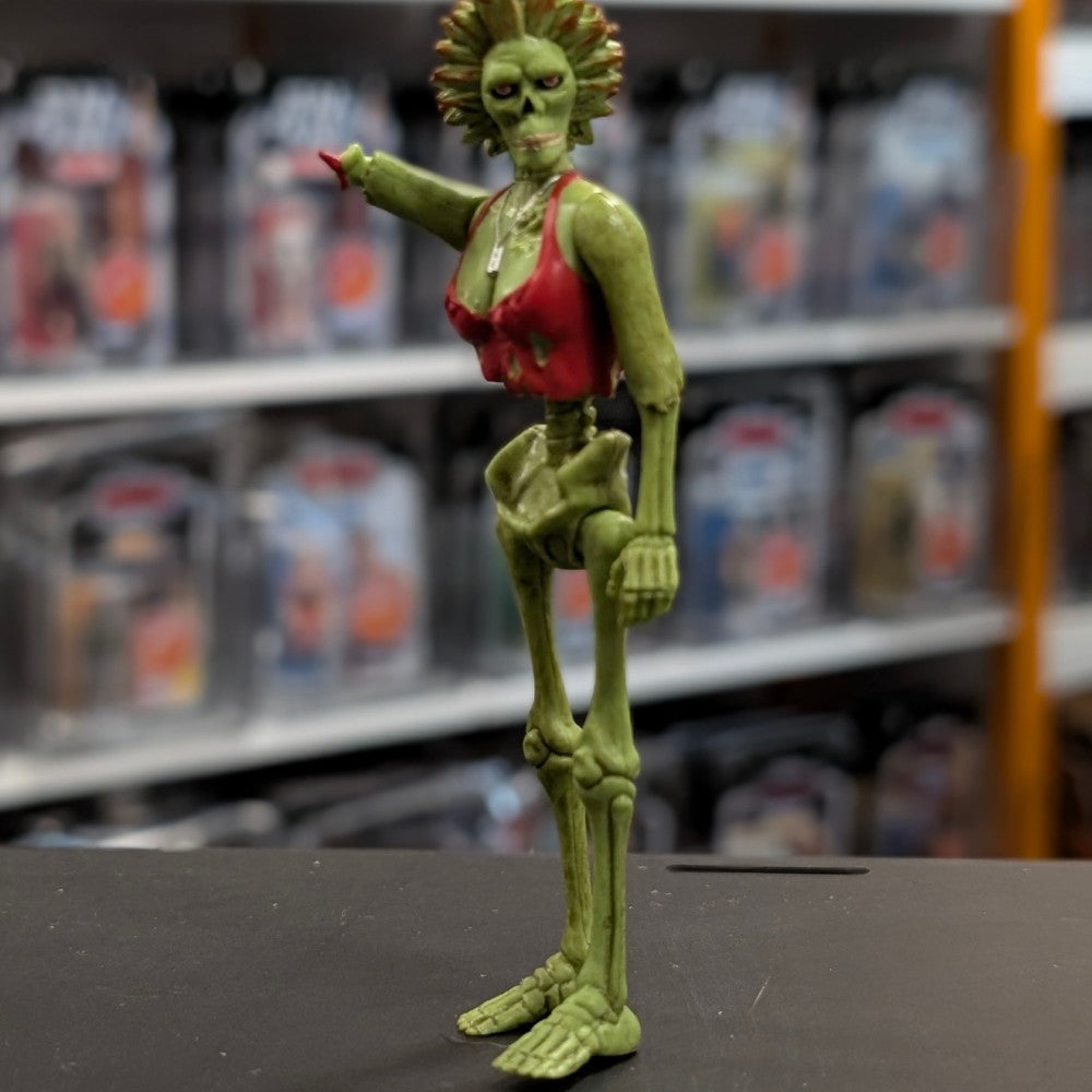 Super7 neon green female zombie figure with torn red top standing in warehouse display setting