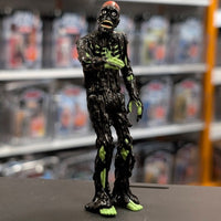 Super7 glossy black tar-covered Tarman zombie figure with neon green skeletal features reaching forward on display surface