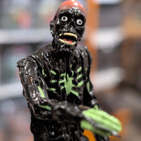 Super7 neon green tar-covered Tarman zombie figure with wide eyes and open mouth in detailed close-up shot