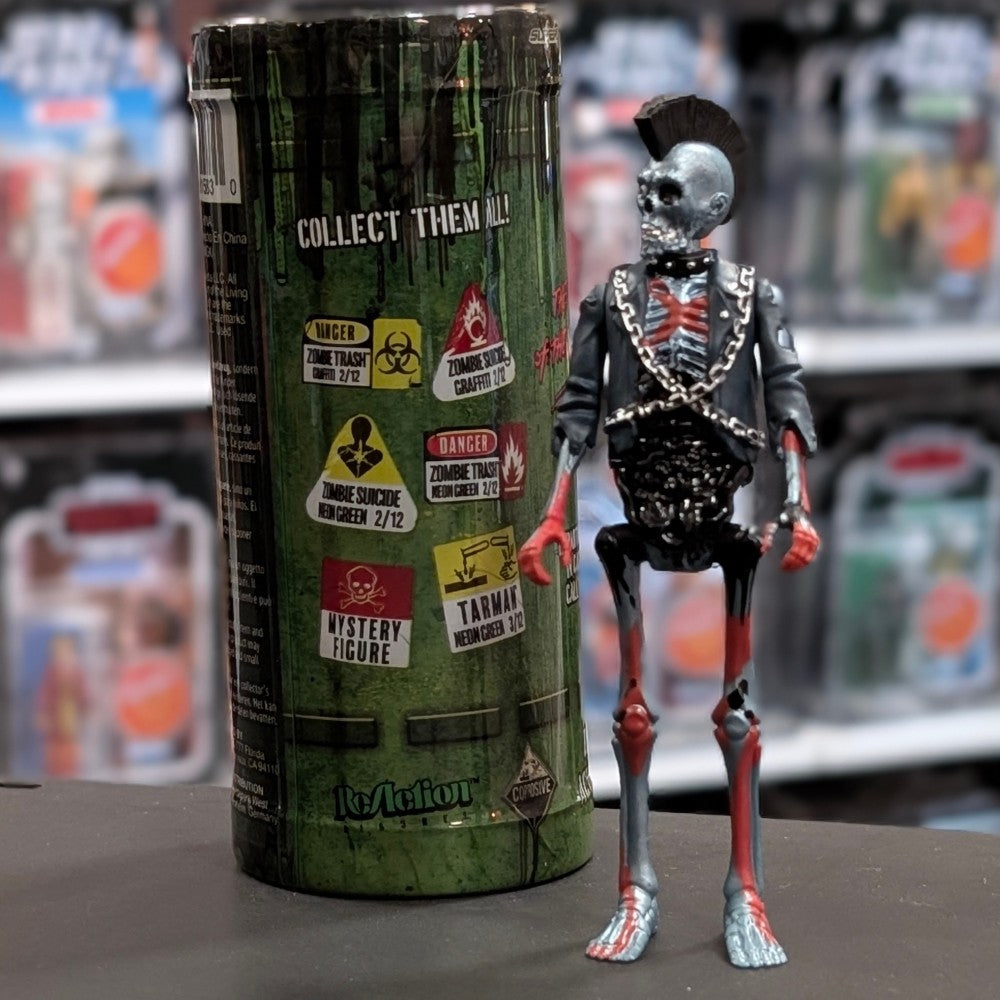 Super7 metallic blue graffiti male zombie figure with skeletal details, mohawk, chains, and black jacket standing next to collectible tube
