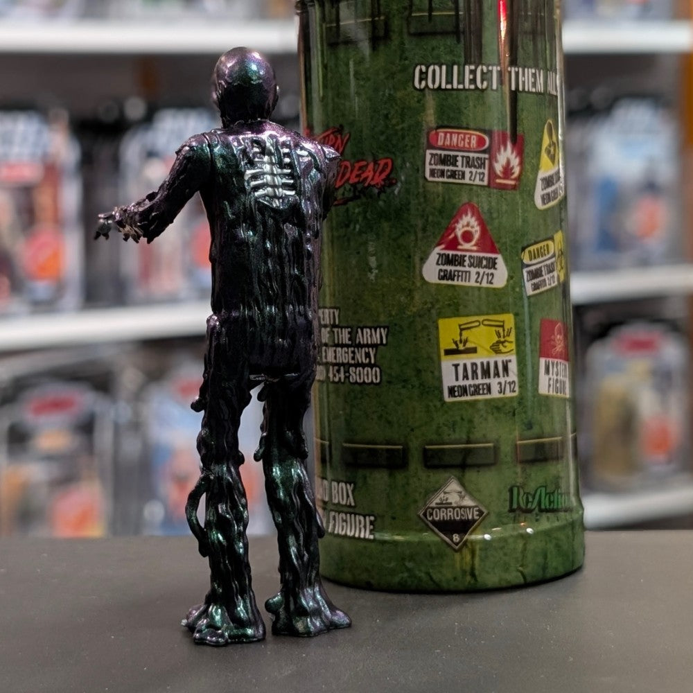Super7 metallic blue tar-covered Tarman zombie figure viewed from back with green collectible container in background