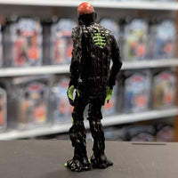 Super7 glossy black tar-covered Tarman zombie figure with neon green skeletal details standing against blurred shelf backdrop