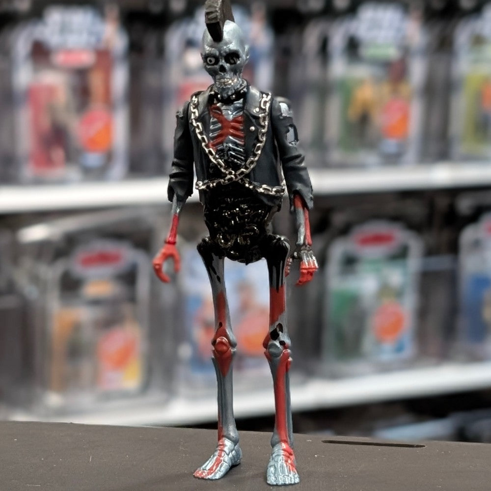 Super7 metallic blue graffiti male zombie figure with skeletal chest, red highlights, mohawk, and black jacket with chains standing upright