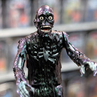 Super7 iridescent tar-covered Tarman zombie figure with wide eyes and open mouth posed reaching forward