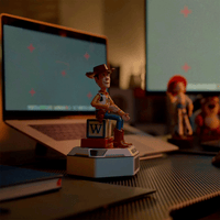 Toy Story Woody mini robot on base by Robesen Robotics with a blurred Jessie robot and laptop in background