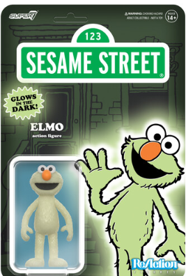 Pale green glowing Elmo figure with orange nose and wide eyes in clear blister pack against Sesame Street backdrop