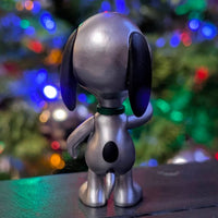 Super7 silver metallic Snoopy figure standing with festive colorful holiday lights in background