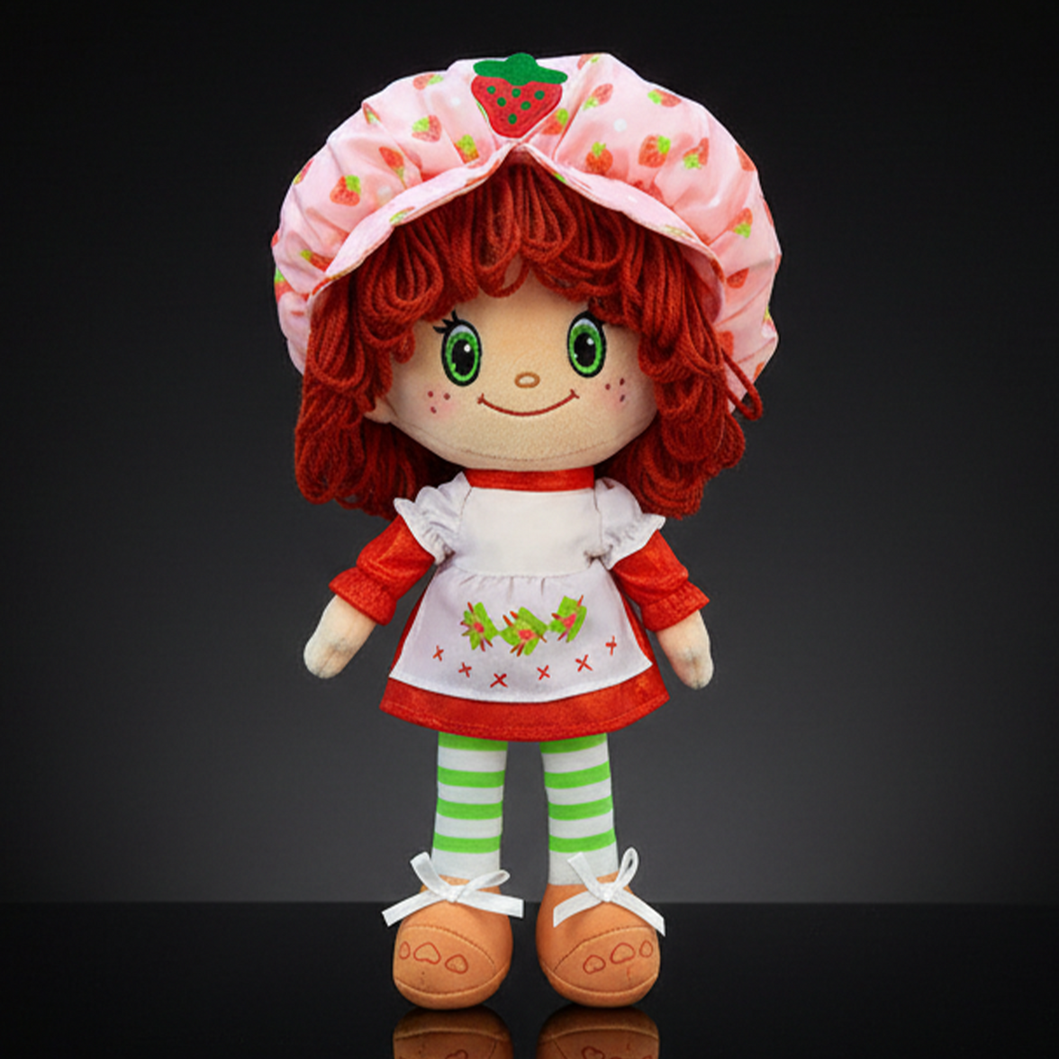 Strawberry Shortcake plush doll with soft yarn hair wearing pink bonnet and red dress by Loyal Subjects on black background