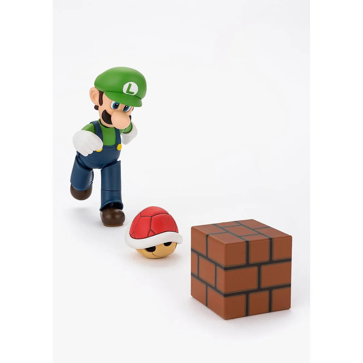 Super Mario Bros Luigi S.H.Figuarts Action Figure by Bandai Tamashii Nations posed with red shell and brick block accessory