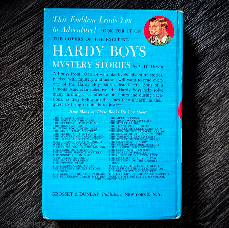 Back cover of 1959 Hardy Boys book The Tower Treasure with blue background and list of titles by Grosset & Dunlap