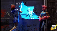 Toy figures in a room with graffiti on the walls, one figure is interacting with a screen displaying another figure.