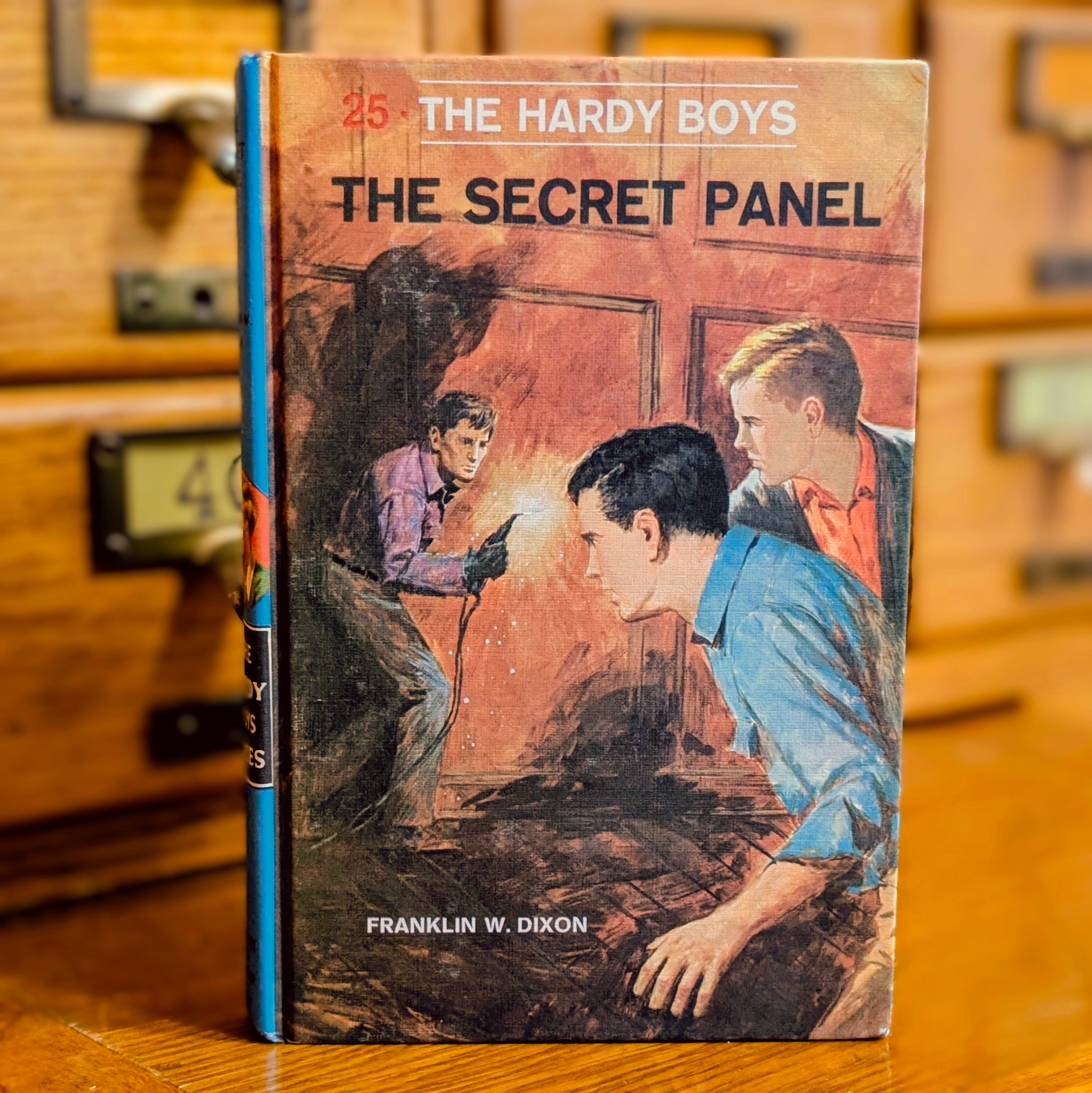 Vintage Hardy Boys book The Secret Panel by Grosset & Dunlap, Inc. showing cover art of three boys investigating a door