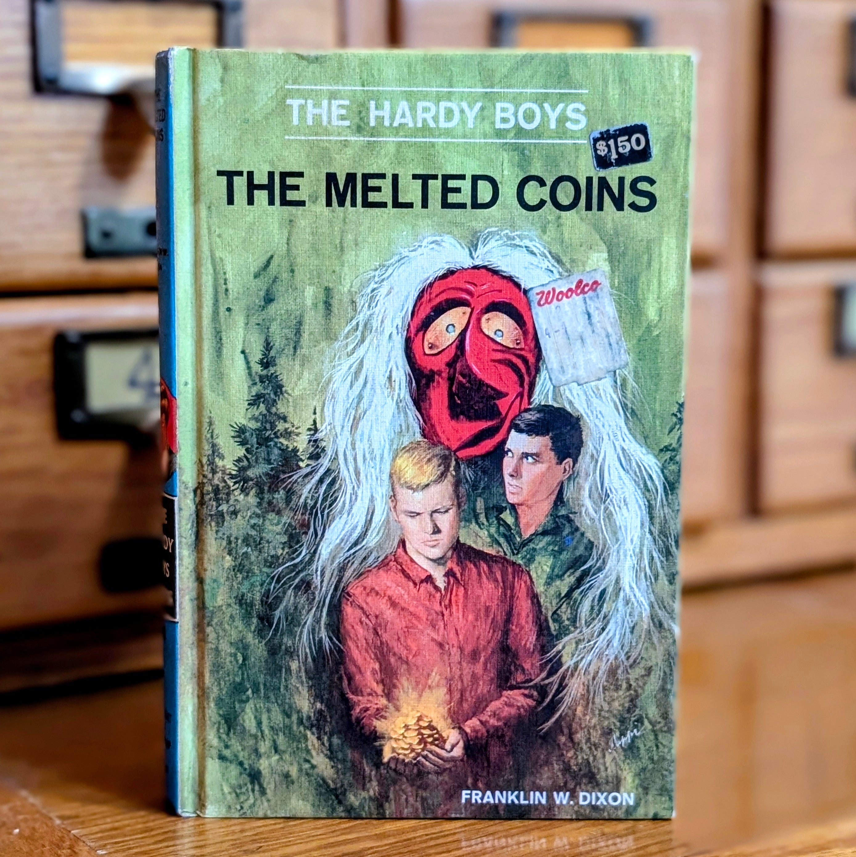 Vintage 1970 Hardy Boys book The Melted Coins by Grosset & Dunlap featuring two boys and a red mask on cover