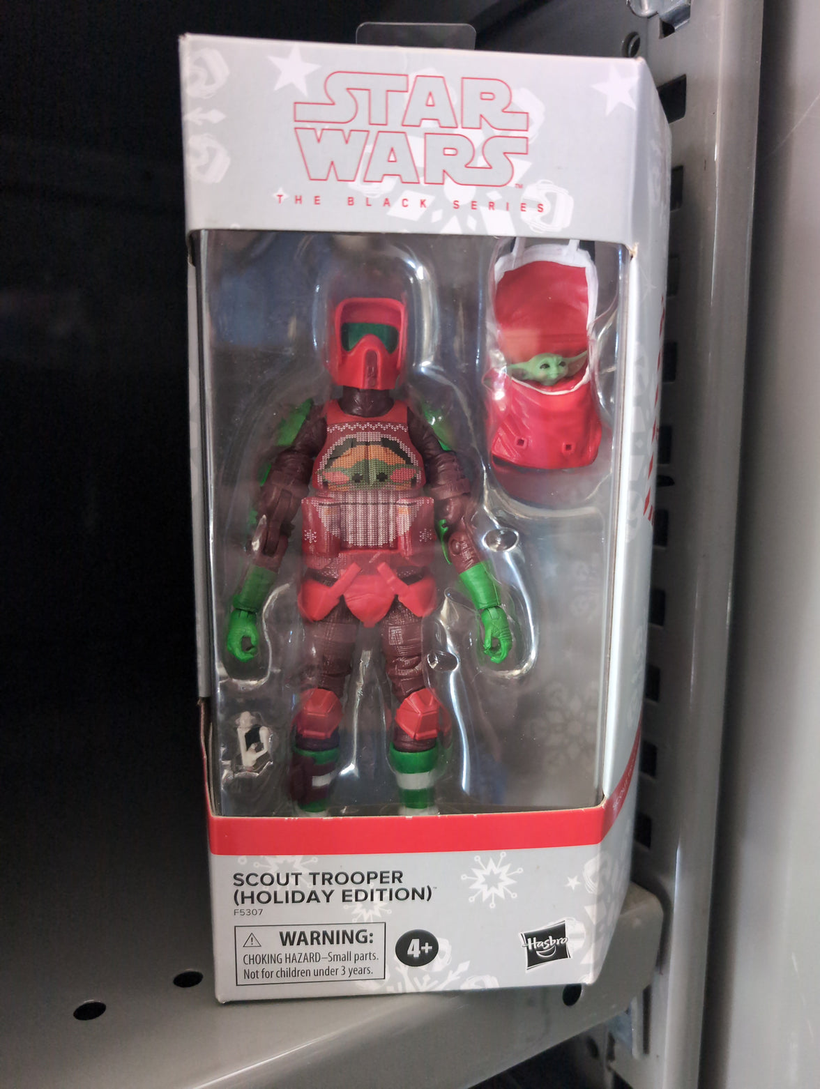 Hasbro Star Wars Black Series holiday Scout Trooper figure in festive red and green armor with Baby Yoda accessory.