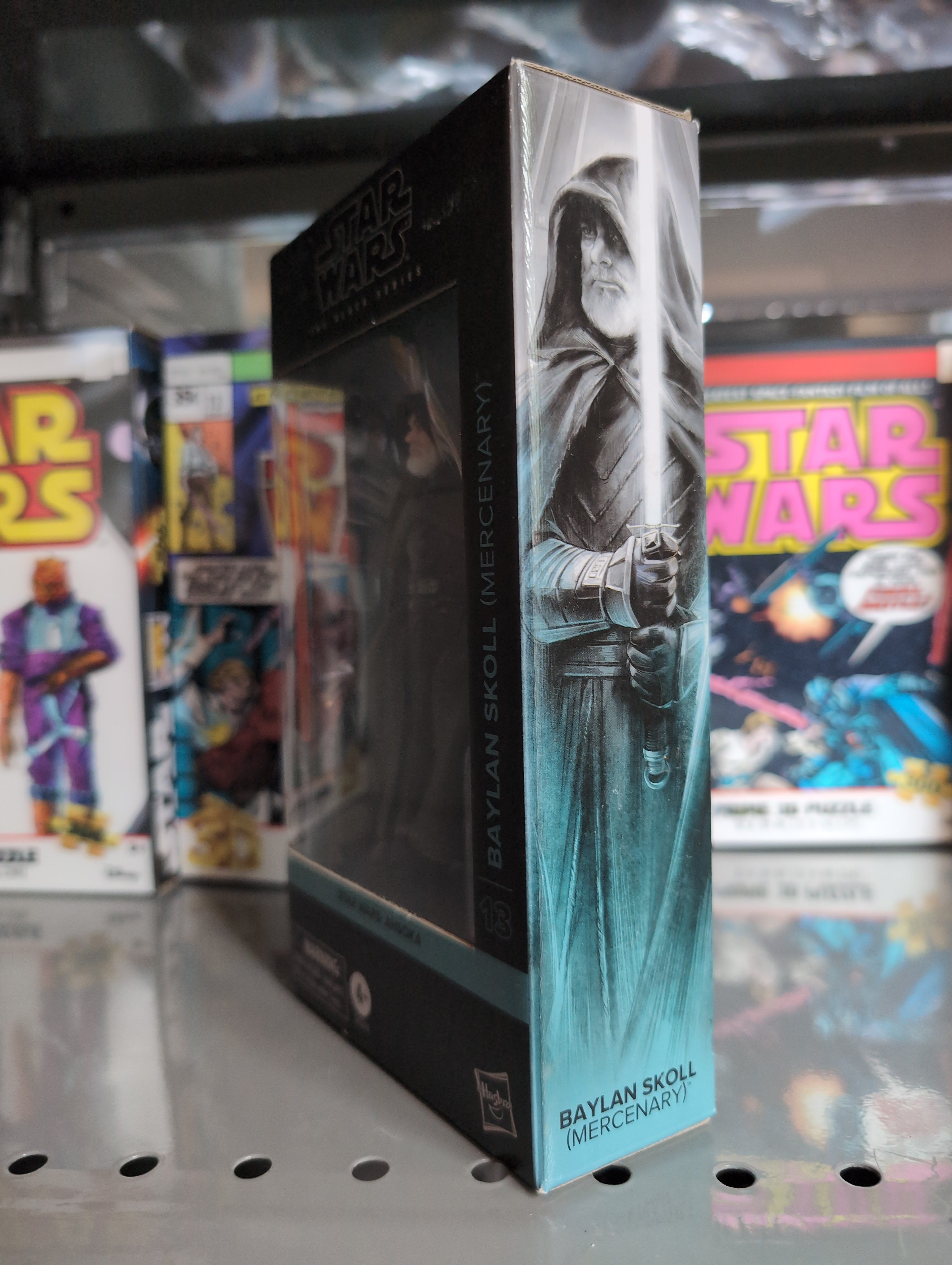 Hasbro Star Wars Black Series Baylan Skoll action figure box with artwork and collectibles in background
